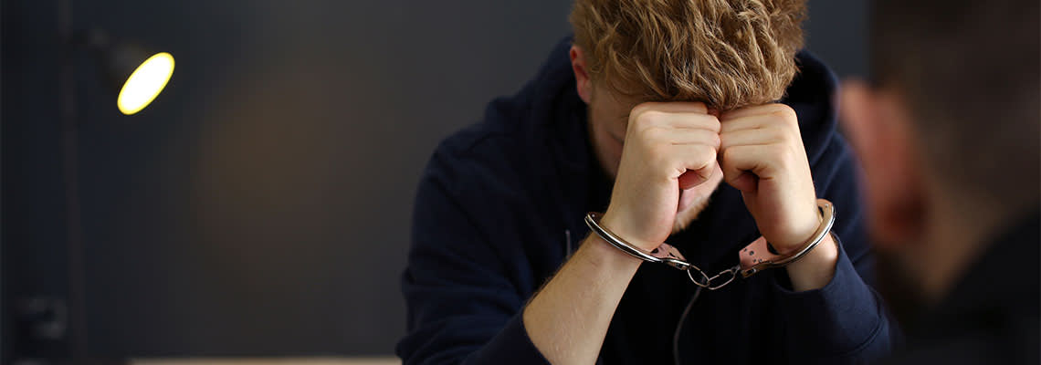 Handcuffed man being interrogated by police officer