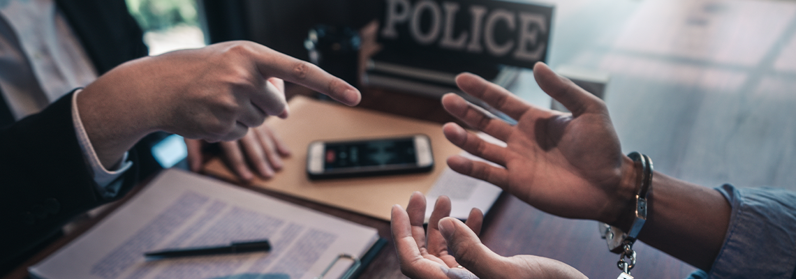Police officer interrogating suspect or criminal man with handcuffs
