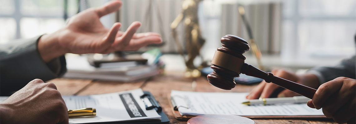 Judge holding a gavel while presiding over a legal discussion among lawyers