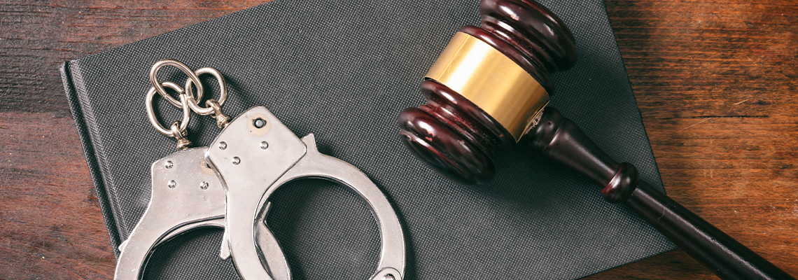 Handcuffs, gavel on book on a wooden background