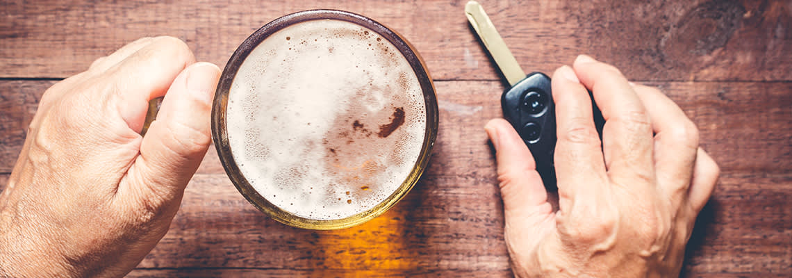 Person holding amber colored drink and car keys