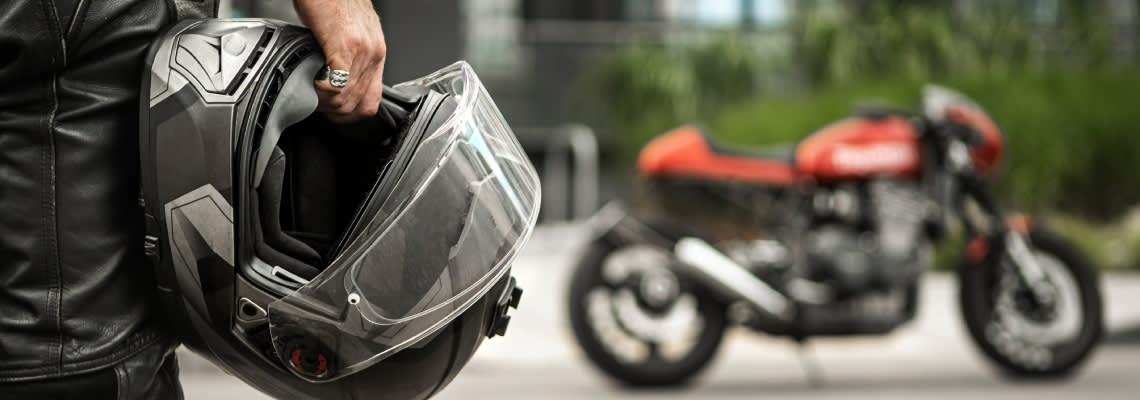 Biker walks to motorcycle holding helmet in hand