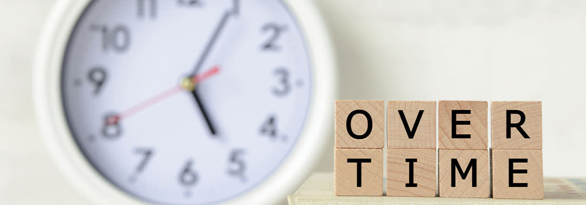 Over Time word on wooden block with clock in background