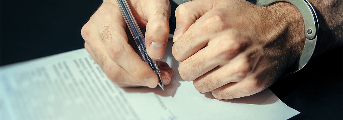 Man signing plea deal paper