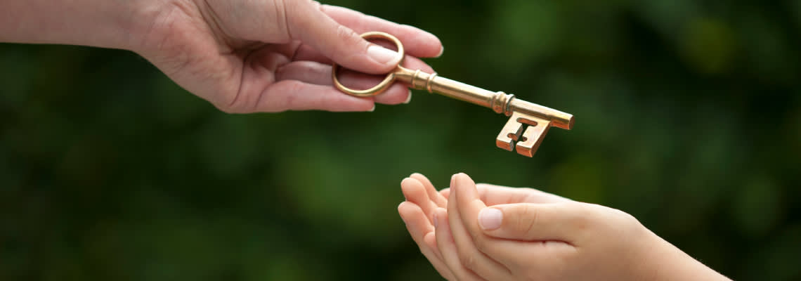 Adult hand handing keys to child hand