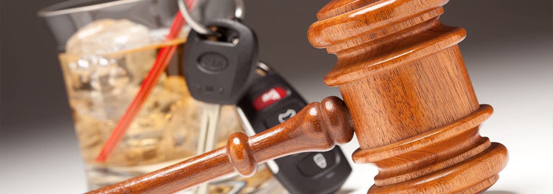 Gavel in Front of Drink with Keys on Straw