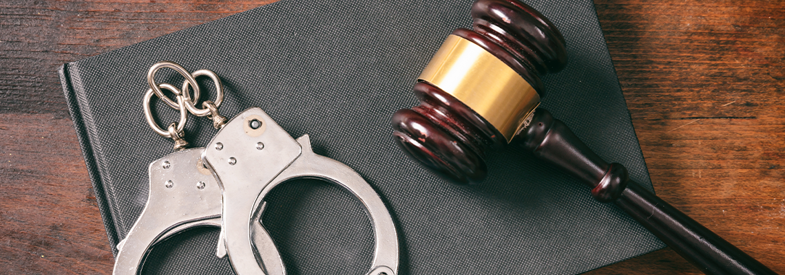 Handcuffs, gavel on book on a wooden background