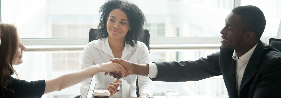 Smiling african businessman handshaking greeting caucasian businesswoman