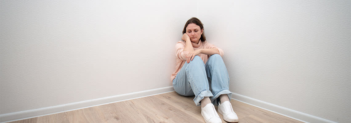 Sad depressed women sitting in corner of a room