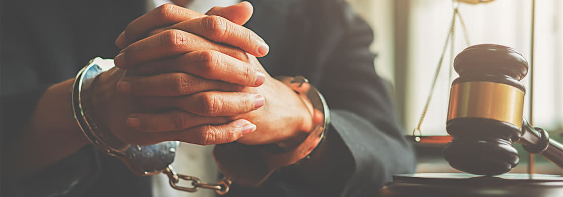 Handcuffed hands and gavel