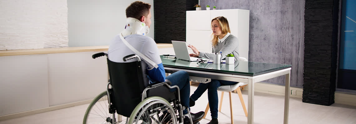 Injured man in wheelchair meeting with insurance agent