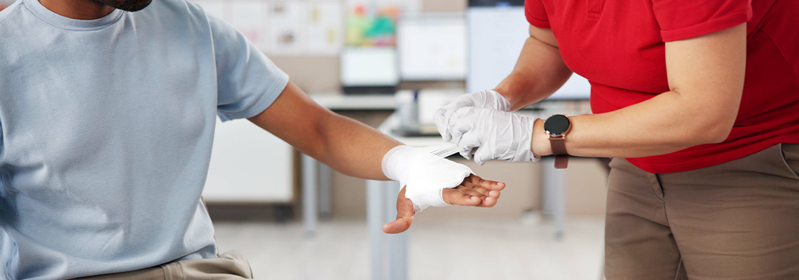 Hands, people and first aid with bandage, teaching or tutorial with care