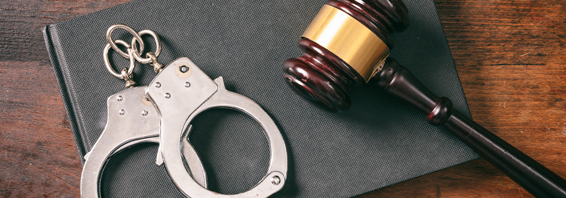 Handcuffs, gavel on book on a wooden background