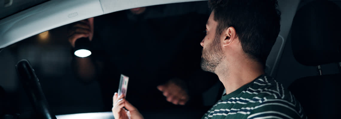 Worried man showing his driving license to police officer