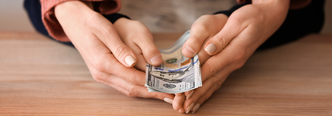 Woman with his son holding dollar banknotes on wooden table