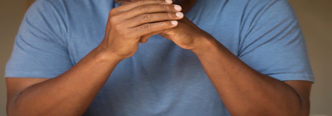 man listening with clasped hands