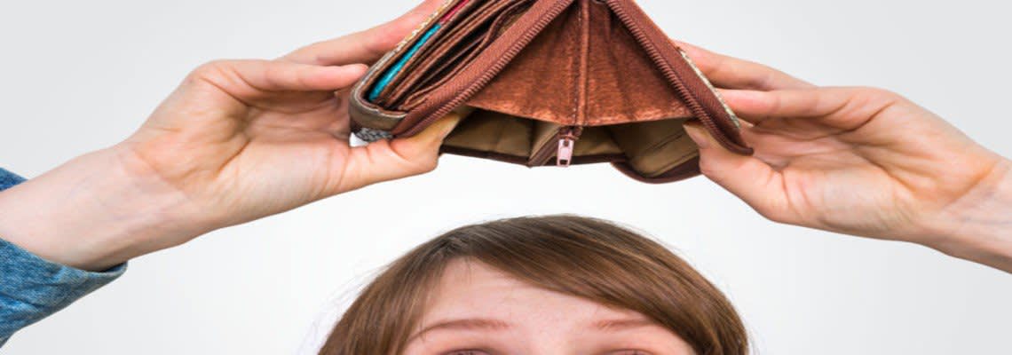 empty wallet being turned upside down by sad woman