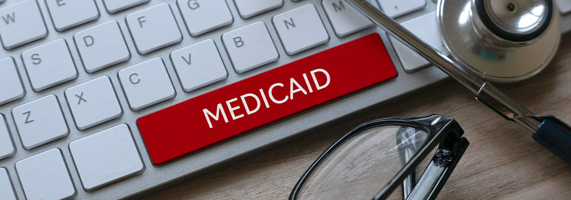 Stethoscope, glasses and computer keyboard with red key written with Medicaid