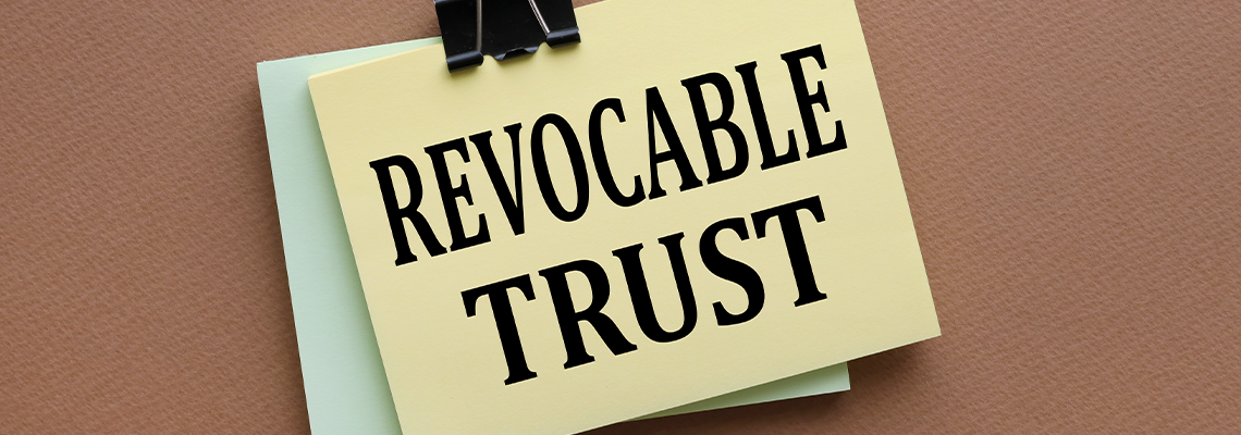 Revocable trust text on yellow sticker with clip. on a dark background