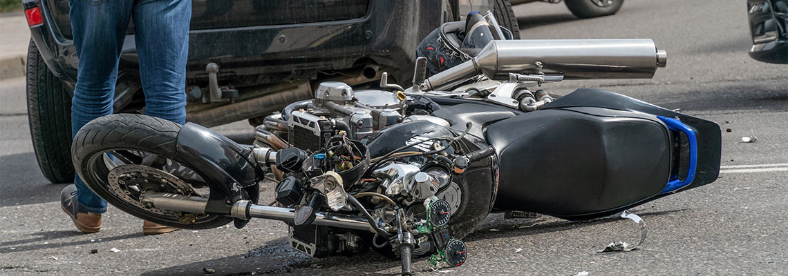 Broken motorcycle closeup beside the car