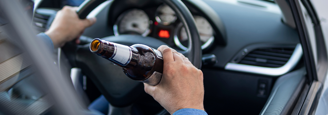 Man in an expensive suit drinks beer at the wheel of a car causing the danger of an emergency