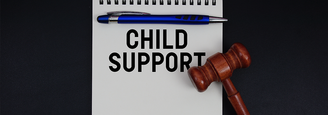 Child Support text written on notepad with gavel on black background