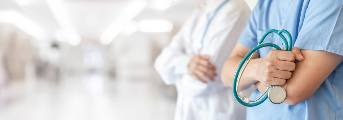 Person in scrubs holding stethoscope next to person in white coat