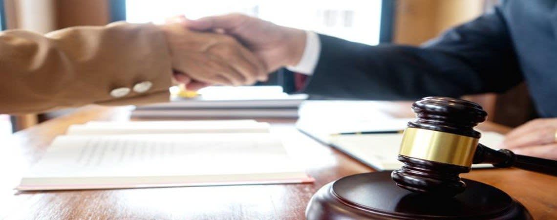 Two people shaking hands in front of a gavel