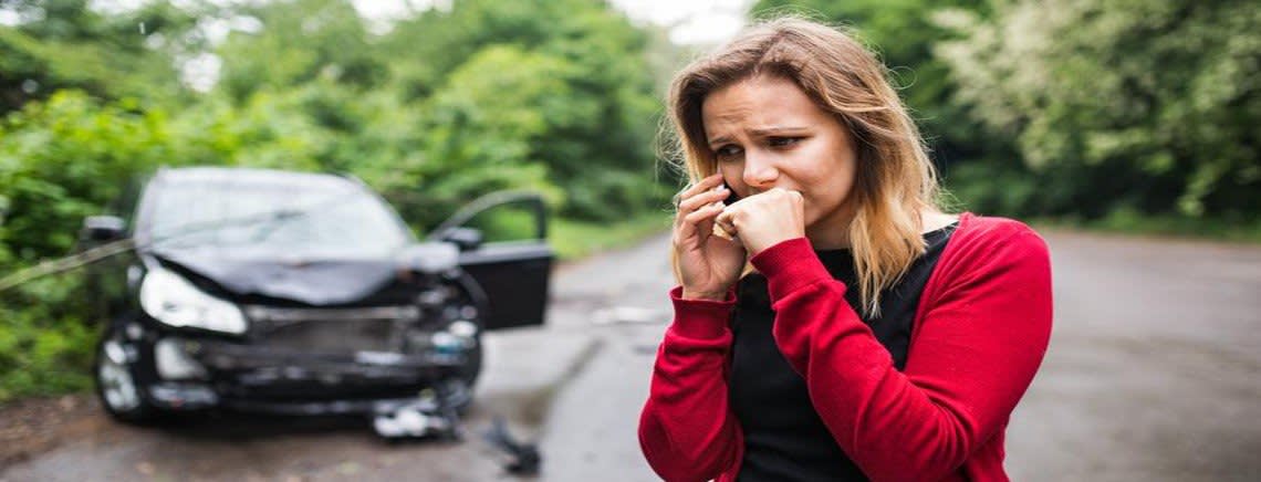 Woman crying on the phone in front of her crashed car