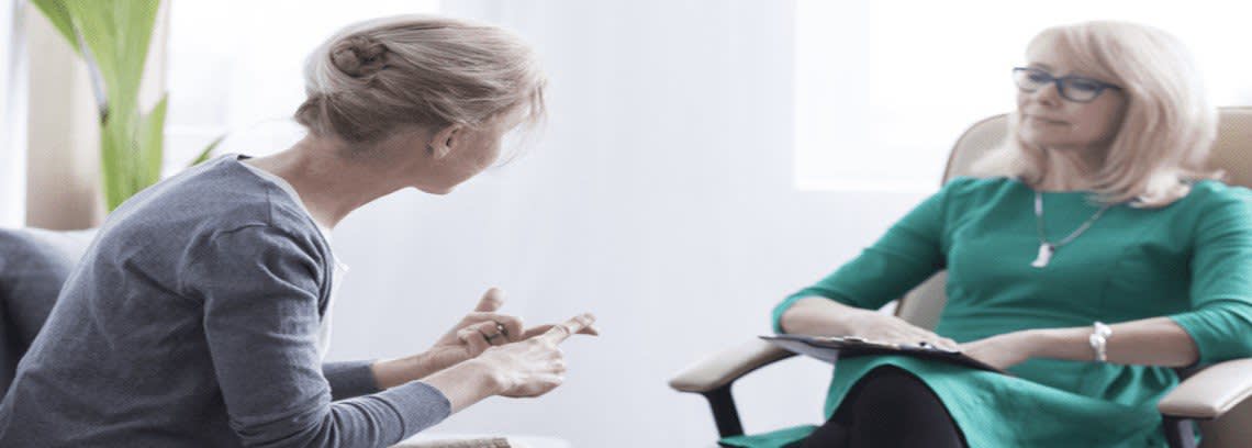 Two women speaking to each other sitting down
