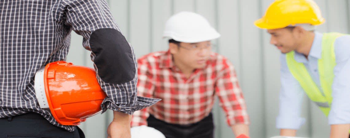 Three construction workers speaking to each other