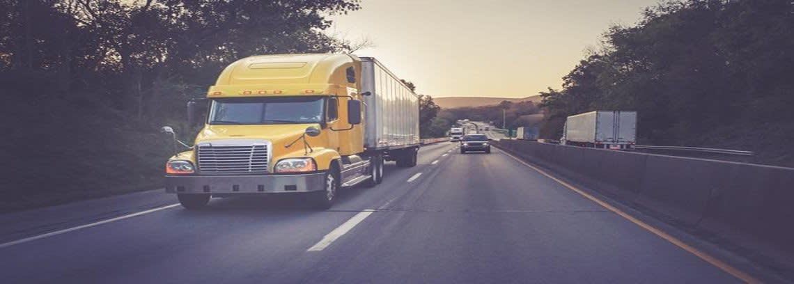 Yellow semi truck driving down the highway