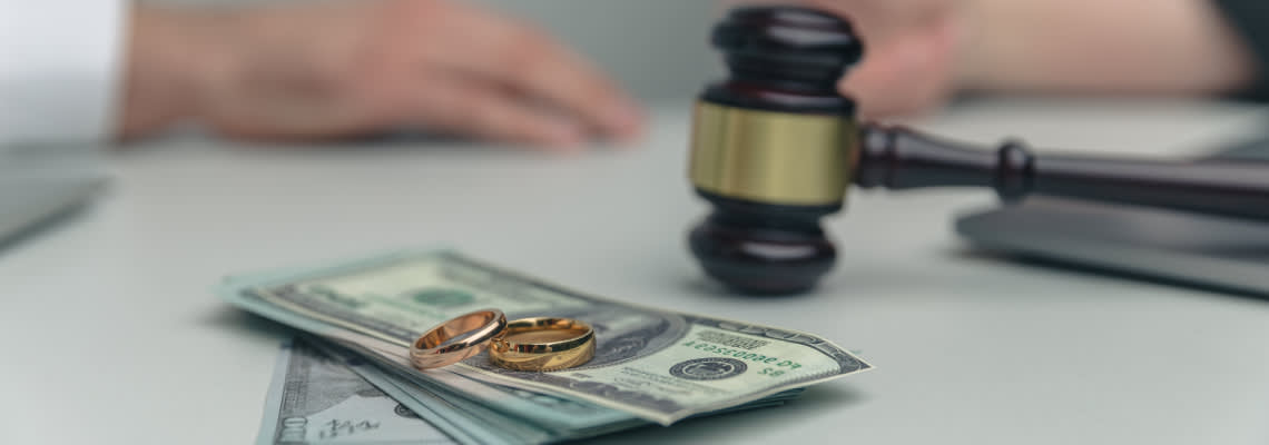 Wedding ring on dollar notes with gavel on table