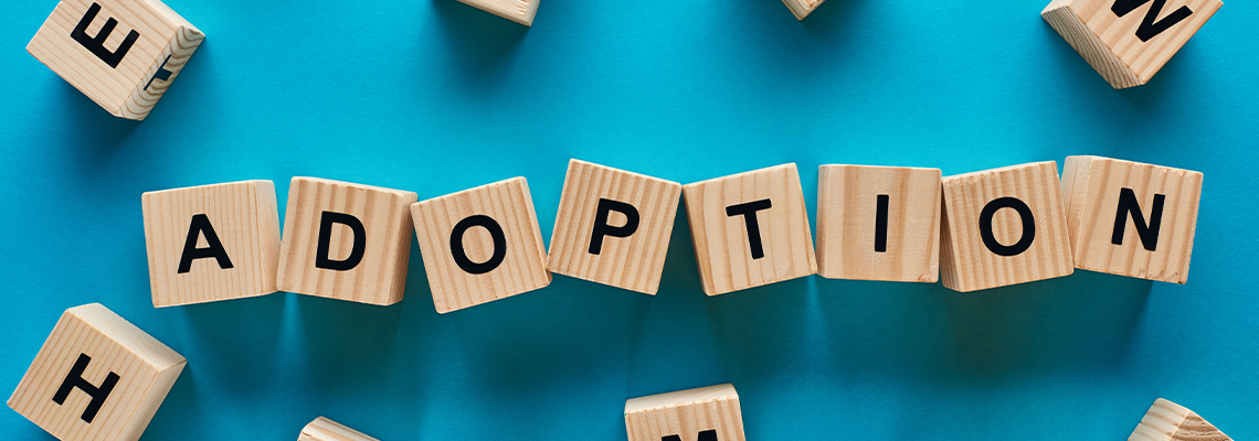 Top view of adoption word made of wooden cubes on blue background