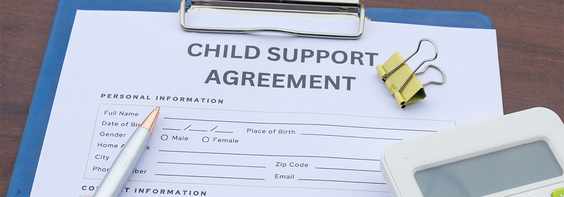 A child support contract clipped in a clipboard with money, a calculator, and a gavel