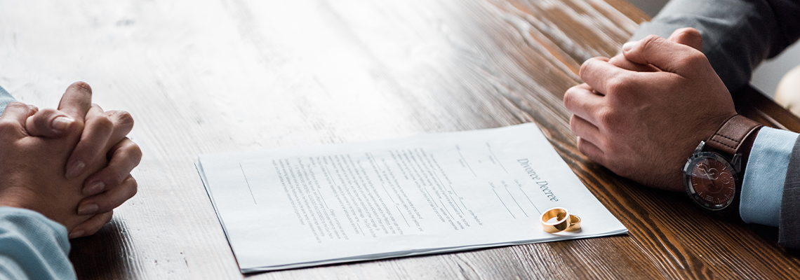Hands of lawyer and client, divorce decree and wedding rings on table