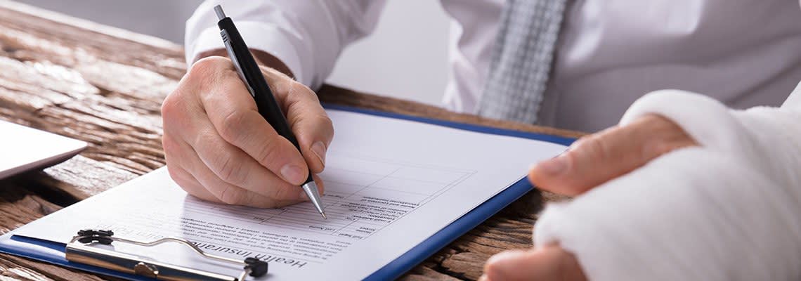 A man with an injured hand fills out a form