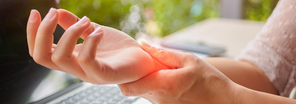 Woman holds her wrist in pain after typing