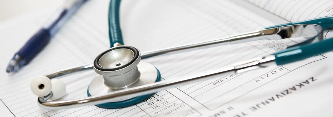 Stethoscope next to pen and medical form