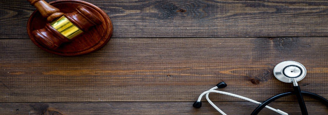 Stethoscope and a gavel on a wooden desk