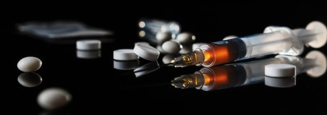 Needle and pills scattered on a surface