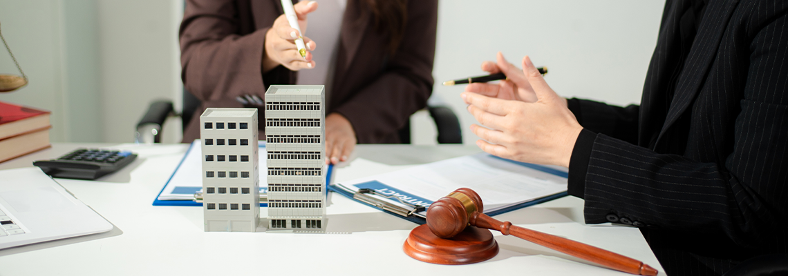 Real estate lawyer reviewing property contract with building model and gavel
