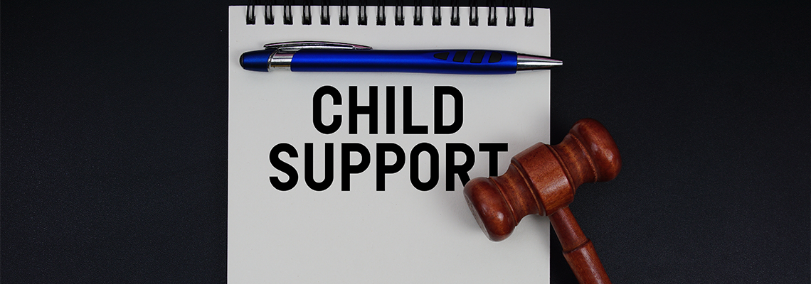Child Support text written on notepad with gavel on black background