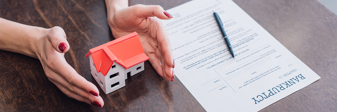 Bankruptcy documents next to a mini model house