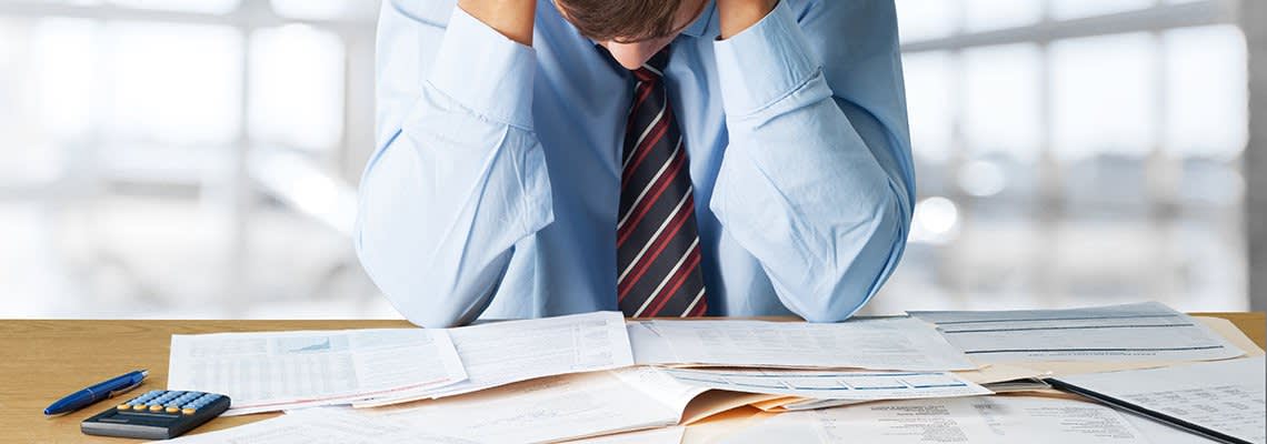 Man with head in hands looking over bankruptcy documents