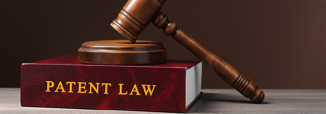 Patent law book and judge's gavel on wooden table