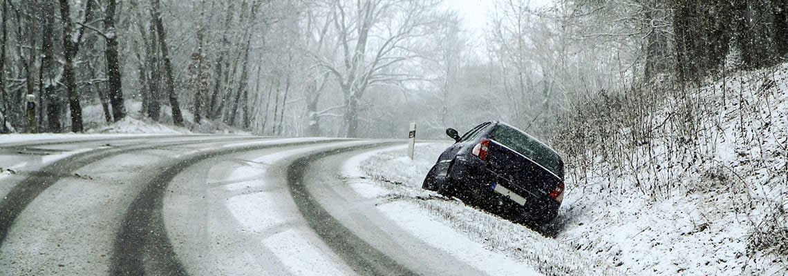 Car in snowy ditch after driving off the road