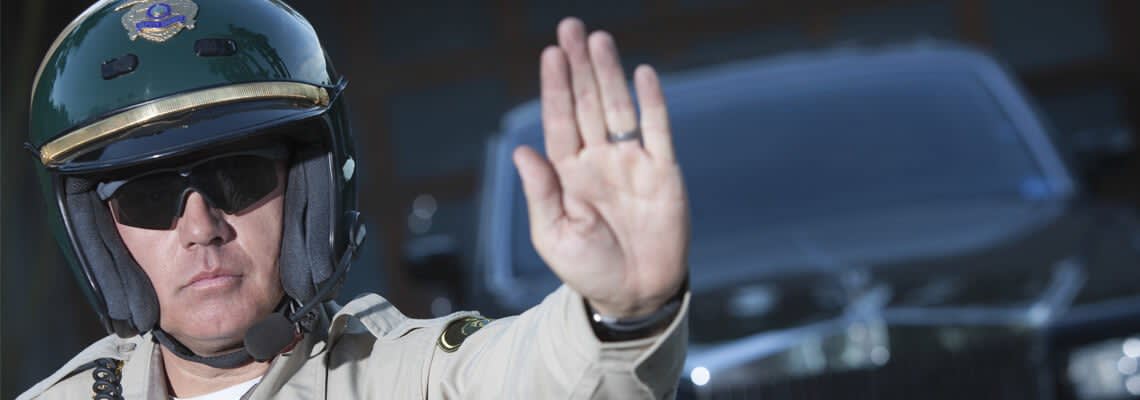 Police officer in helmet holding hand up to signal stopping