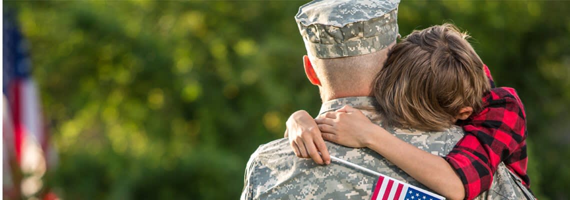Veteran Hugging a Boy Holding an American Flag