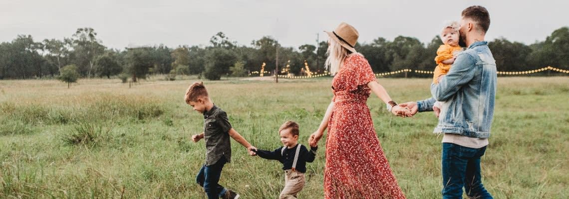 Family of five holding hands in a field